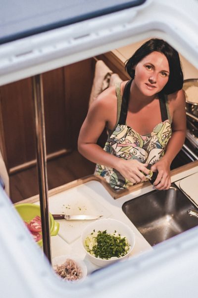 Portrait of young woman through yacht hatch preparing food in kitchen, Croatia